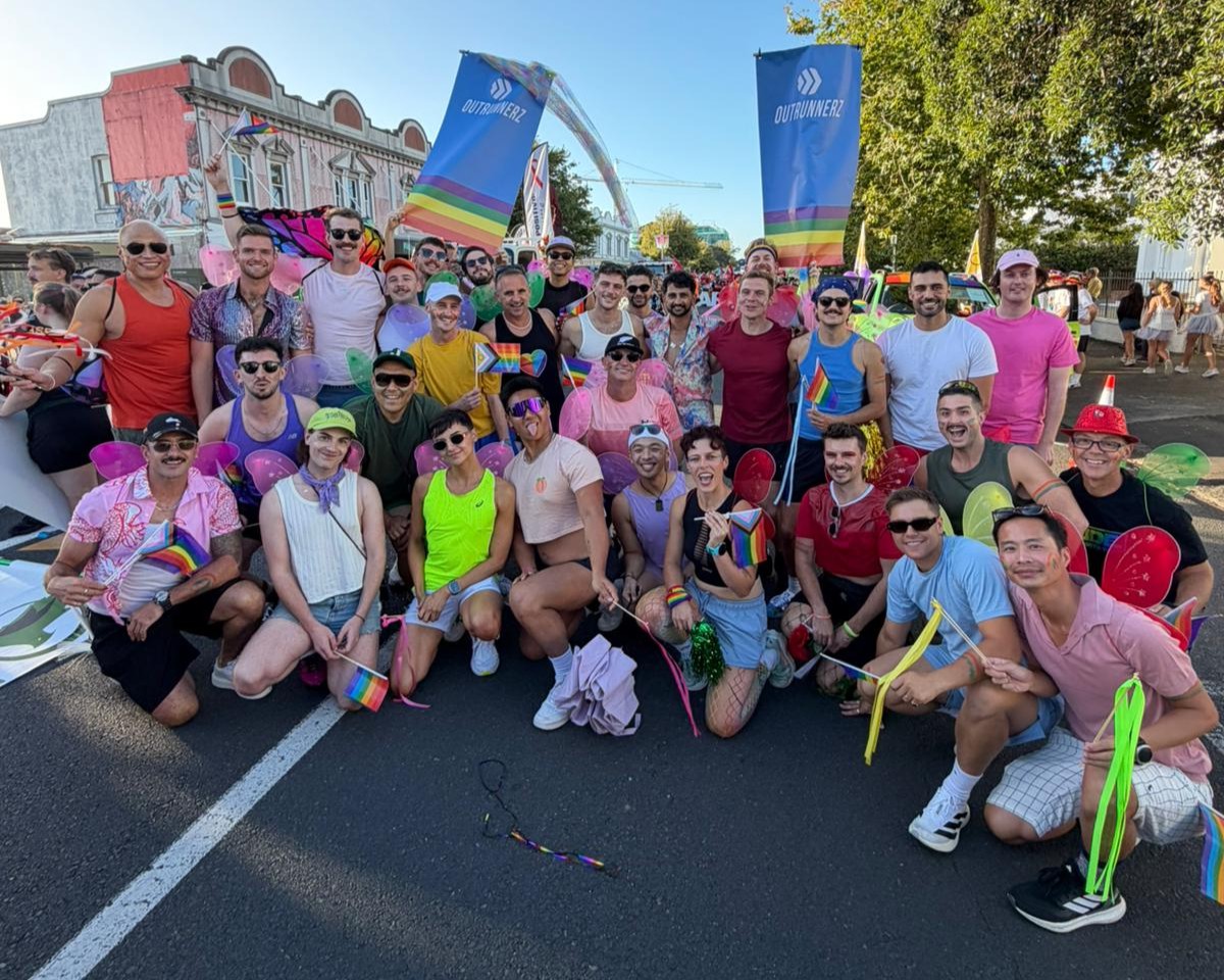 Big group of runners in active wear posing for a photo on a city street.