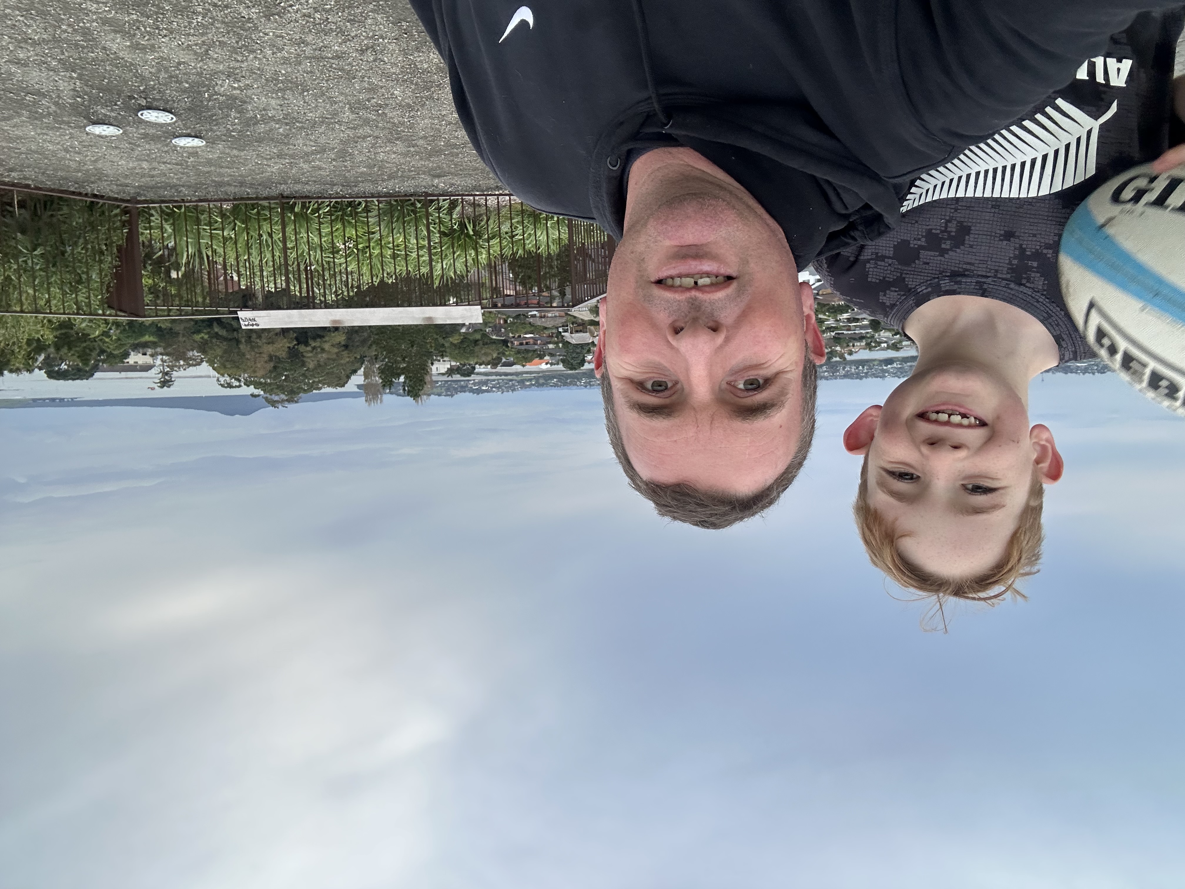 Selfie a man and a boy outdoors, behind them the Auckland landscape and Rangitoto.