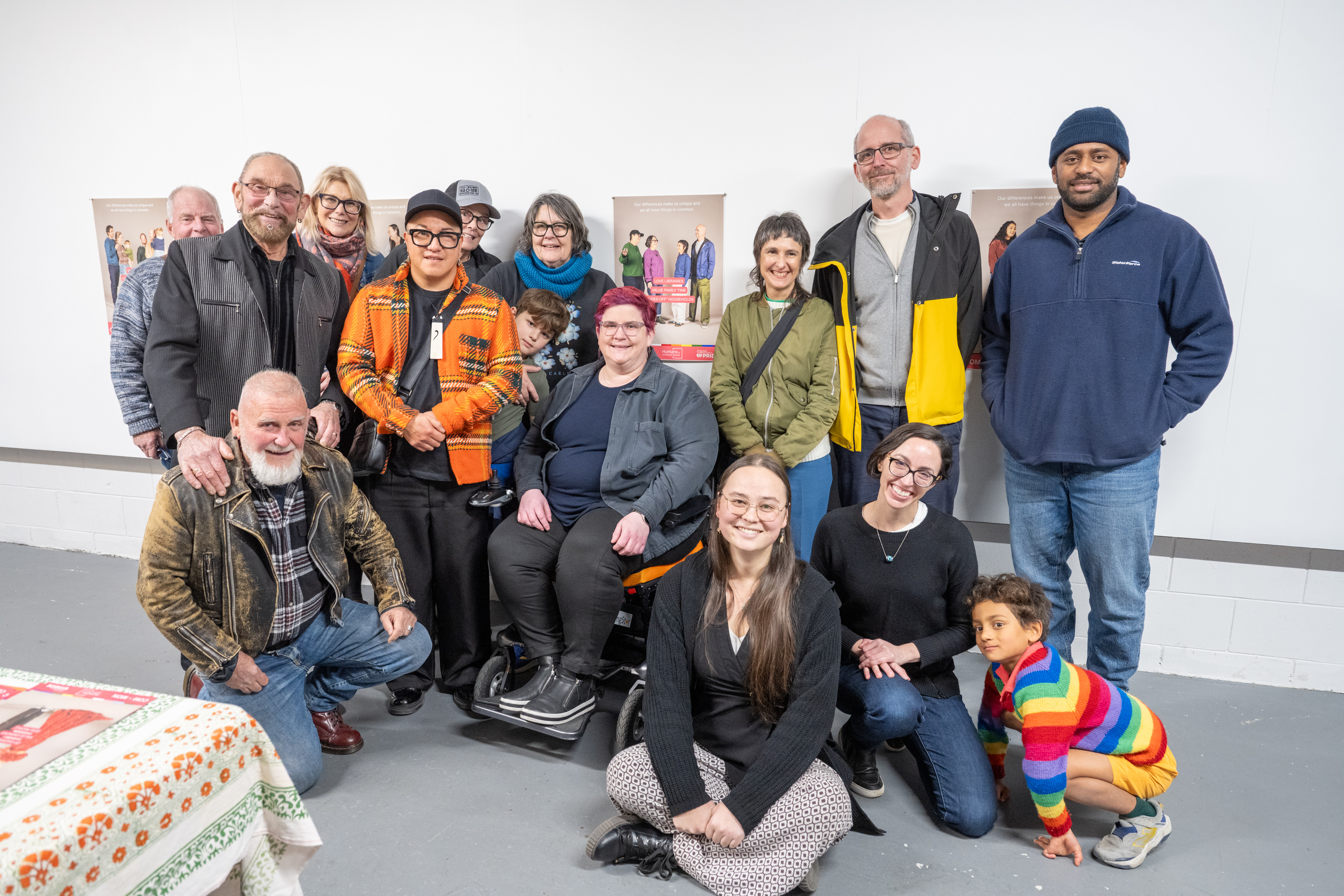 A diverse group of community members posing together in front of campaign posters at a community event.