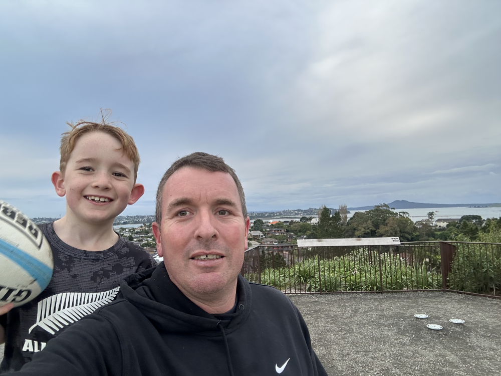 Selfie of a man and a boy with a landscape view of a mountain behind them.