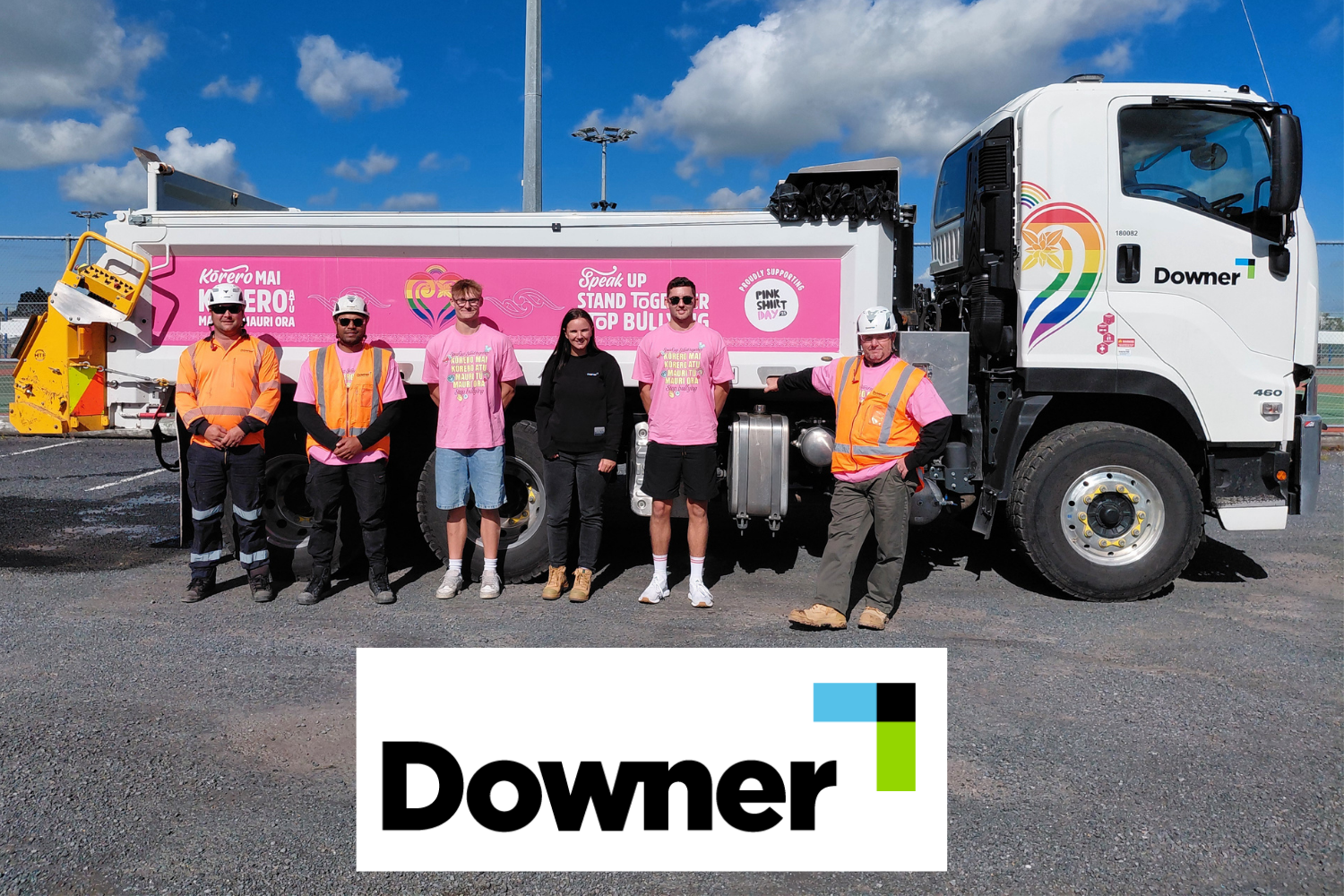 Group of people in Pink Shirt Day T-shirts, hi-vis vests and hard hats stand in front of a truck wrapped in Pink Shirt Day branding.
